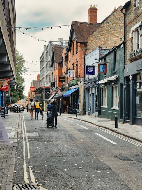 An aerial view of a busy street scene on Chessington High Street, featuring a small white building with a flat roof, accommodating a shop with an awning and display windows. Several parked vehicles, i